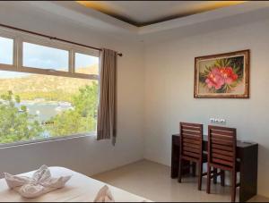 a bedroom with a table and two chairs and a window at New Anugrah Hotel in Teluk Nara +8 photos