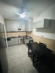a small kitchen with a table and a ceiling fan at Spacious apartment 100m from the beach and promenade in Torrevieja