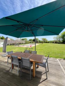 ein Holztisch mit Stühlen und einem großen grünen Sonnenschirm in der Unterkunft 2 Chambres 25m2 à 9min circuit du Mans in Voivres-lès-le-Mans