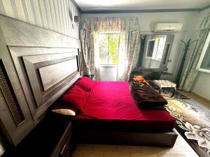 a large red bed in a room with a window at شقة غرفتين نوم بحديقة خاصة في المعمورة الشاطئ دور أرضي in Alexandria