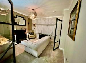 a living room with a white leather couch in a room at Olive Tree Cottage in Golcar