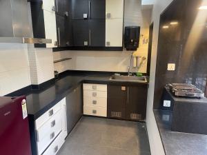 een keuken met zwart-witte kasten en een wastafel bij Penthouse retreat by speed homes in Calcutta
