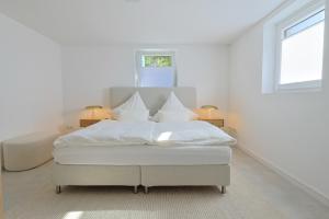 une chambre blanche avec un lit avec des draps et des oreillers blancs dans l'établissement Souterrain in Timmendorfer Strand - Niendorf Ostsee, à Timmendorfer Strand
