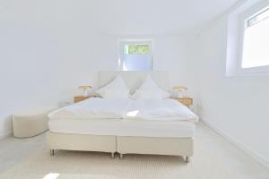 une chambre blanche avec un lit avec des draps et des oreillers blancs dans l'établissement Souterrain in Timmendorfer Strand - Niendorf Ostsee, à Timmendorfer Strand