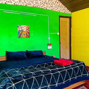 a bedroom with a green wall and a bed at Mountain Breeze in Kasol