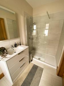 a white bathroom with a shower and a sink at Roxy's Place in Portballintrae