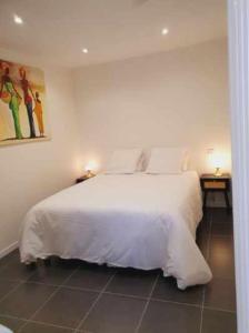 a bedroom with a white bed and two night tables at Maison avec garage 24 HEURES DU MANS VOITURES et toute manifestation in Le Mans