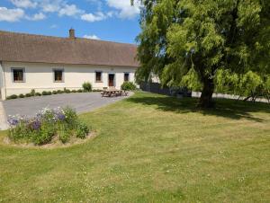 a building with a tree and a grass yard at La Ferme Des Pierrettes in Menneville