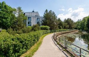 a walkway next to a river in front of a building at Panoramic View PH By The Sea in Palanga