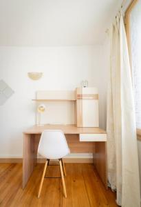 a desk with a white chair next to a window at Appart' des Tours de La Rochelle in Aytré