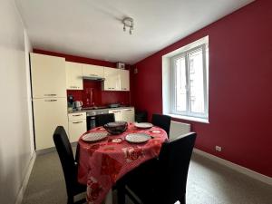 a kitchen with a table with a red wall at T3 Hyper centre Place des Vosges in Épinal