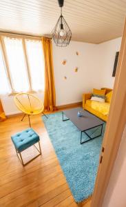 a living room with a yellow bed and a blue rug at Appart' des Tours de La Rochelle in Aytré