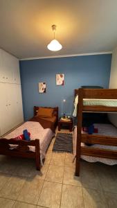 a bedroom with two beds and a blue wall at Το Φιλόξενο Σπιτάκι! - The Friendly Nest ! in Paralion astros