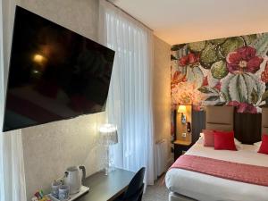 a hotel room with a bed and a tv on the wall at HOTEL ARVERNA VICHY - ClT'HOTEL in Vichy