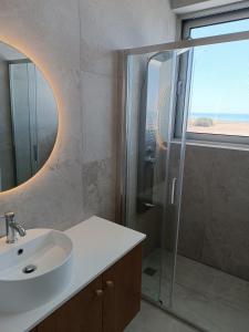 a bathroom with a sink and a glass shower at Blue Aura Beach villa Larnaca in Pervolia