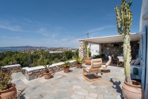 a patio with chairs and potted plants and a building at Anemoessa Cycladic House in Angairiá