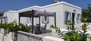 a white house with a table and chairs and an umbrella at Chrysiis House 1 in Maltezana
