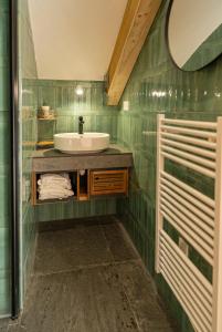 a green tiled bathroom with a sink and a mirror at Chalet du Trappeur in Les Orres