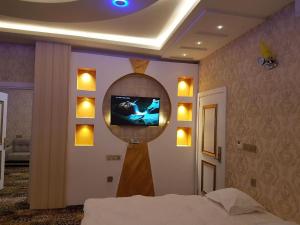 a bedroom with a tv on the wall and a bed at Virar Hotel Erbil in Erbil