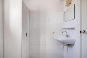 a white bathroom with a sink and a mirror at Koekoek I Modern Huis met Privé Tuin in Zwiggelte