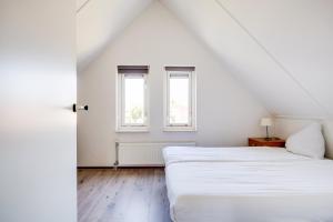 a white bedroom with two beds and a window at Koekoek I Modern Huis met Privé Tuin in Zwiggelte