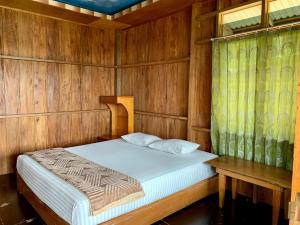 a bedroom with a bed and a wooden wall at Bagoes View Cottages in Maninjau