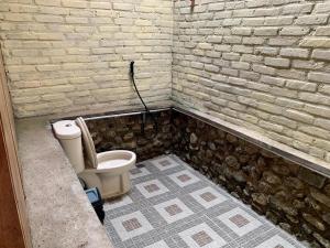 a bathroom with a toilet in a brick wall at Bagoes View Cottages in Maninjau