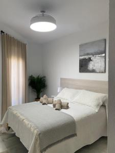 a bedroom with a large bed with two stuffed animals on it at Apartamento Capillera 9 in El Puerto de Santa María