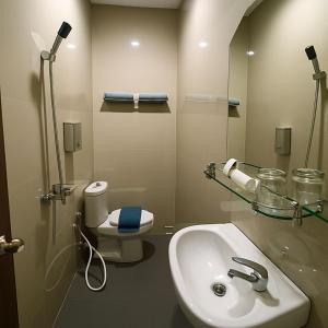 a bathroom with a sink and a toilet and a mirror at Ipoenk Hotel Malioboro in Sentool