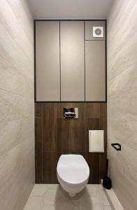 a bathroom with a white toilet and wooden walls at Нова квартира поруч з метро in Kyiv