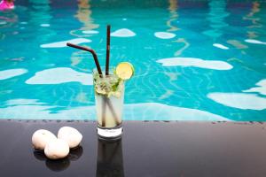 a drink sitting next to a swimming pool at Swiss Flora Royal Hotel Riyadh in Riyadh