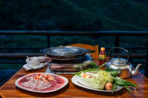 a table with two plates of food and a grill at Whispering Mok At Sapan in Ban Huai Ti