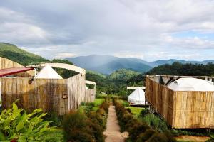 a garden with several wooden fences and tents at Koya Homestay โกญ่า โฮมสเตย์ in Mae Rim