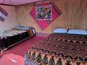 two beds in a room with a blanket on the wall at Uros Casa de Yolanda in Puno