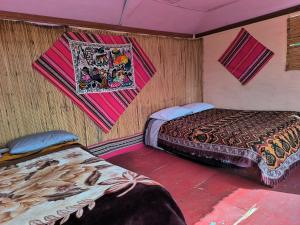 two beds in a room with a painting on the wall at Uros Casa de Yolanda in Puno