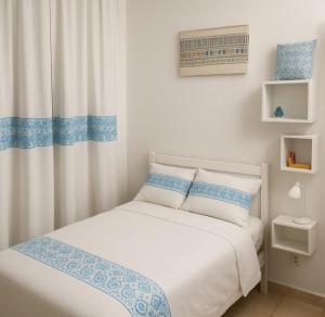 a small bedroom with a white bed with blue accents at Casa Silius in Silìus