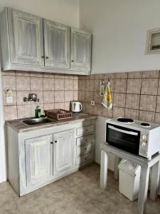 a kitchen with white cabinets and a sink and a stove at Irene Studios in Arillas