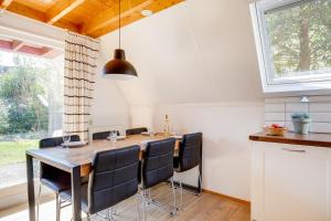 a dining room with a wooden table and black chairs at Nachtegaal I Vakantiewoning met Mooie Tuin in Zwiggelte