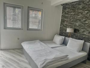 a white bedroom with a bed and two windows at OneRoom in Ohrid