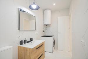 a white bathroom with a sink and a mirror at NEW! Stunning modern 2BR apt next to Feria in Seville