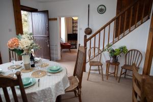 a dining room with a table with a vase of flowers at Garnllys Farmhouse Fishguard in Fishguard +23 photos