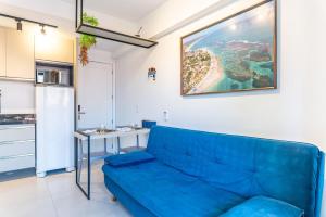 a living room with a blue couch and a kitchen at Flat no Centro 1 Quarto com varanda - 50m Piscinas das Naturais in Porto De Galinhas