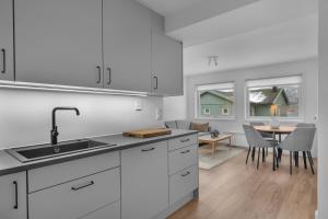 une cuisine avec des armoires blanches et une table avec des chaises dans l'établissement 2-bedroom modern apartment in Tromsø, à Tromsø