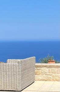 a wicker bench sitting next to a stone wall at Villa Anatoli in Epáno Kefalás