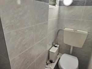 a bathroom with a toilet and a tiled wall at Dimana Maisonette, 150m from Fourka Beach in Skála Foúrkas