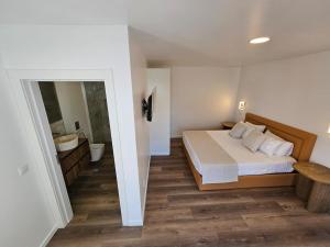 a bedroom with a large bed and a bathroom at Vila Ladeira dos Zimbreiros - 3 bedroom, Jacuzzi, gym, AC, Pool with optional heated water in Paul do Mar +34 photos