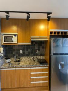 a kitchen with wooden cabinets and a stainless steel refrigerator at Espaçoso II Apartamento com Piscina - Metrô Brás in Sao Paulo