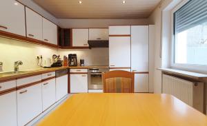 a kitchen with white cabinets and a wooden table at Ferienwohnungen Sonne in Siegsdorf