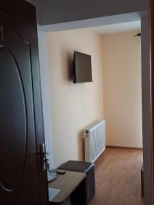 a room with a table and a tv on the wall at Pensiunea Krystinne in Peştişu Mare