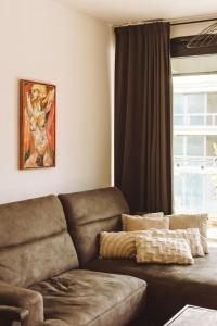 a living room with a brown couch and a window at Apartament Warmiński Port 50m od jeziora in Olsztyn
